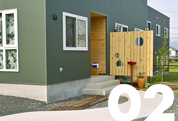 緑の外壁や曲線のアプローチが印象的な一戸建て住宅のエクステリア